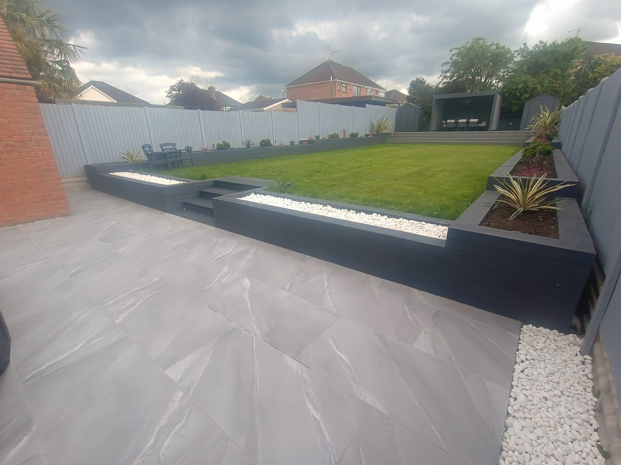 Grey slate patio with timber planters and ornamental grasses